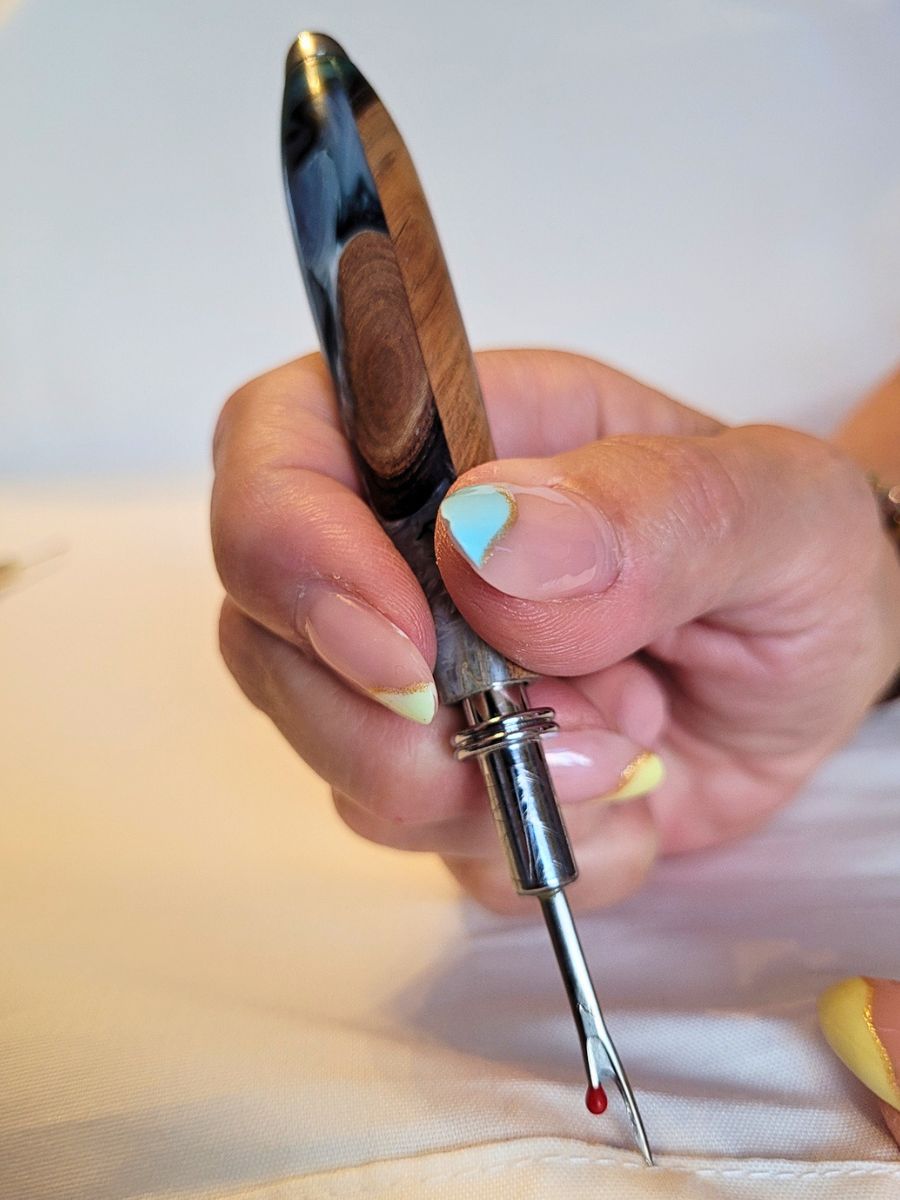 Découd‑vite artisanal hybride en résine époxy bleue et blanche et racine de hêtre, utilisé pour découdre une couture.