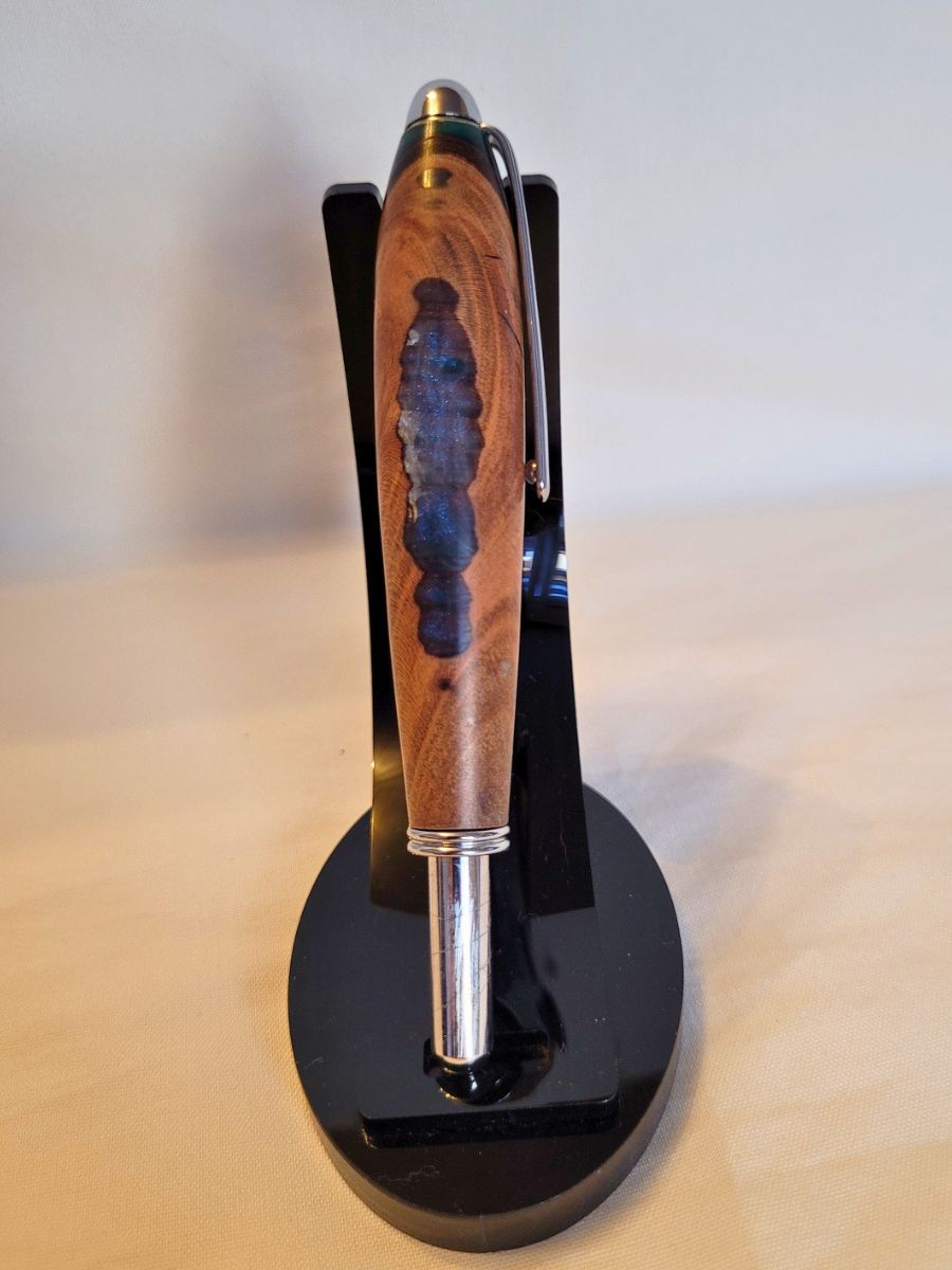 Découd‑vite artisanal hybride en résine époxy bleue et blanche et racine de hêtre, finition chromée, design évoquant une île sur l’océan.