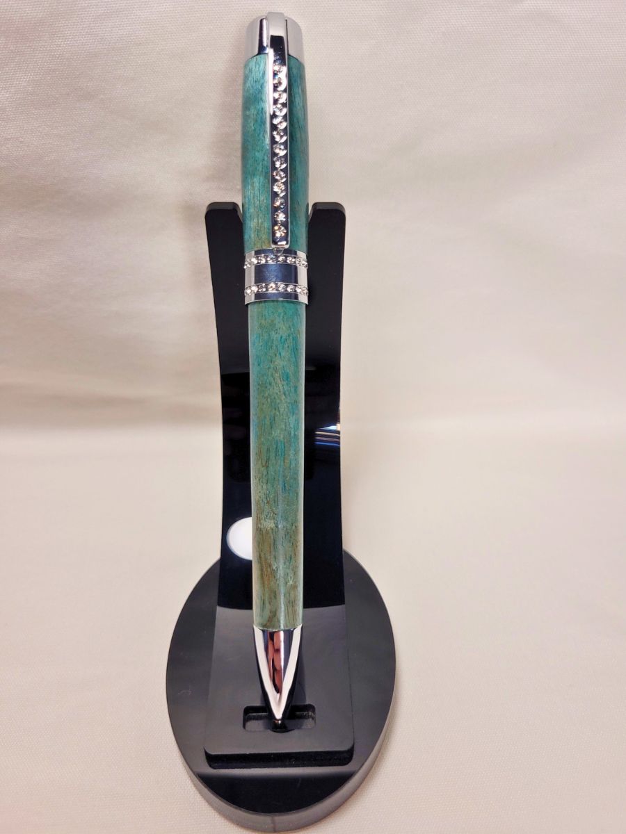 Stylo Princesse bleu aux reflets turquoise sur support noir — stylo en bois de bouleau, placage chrome et strass blancs, création artisanale raffinée.