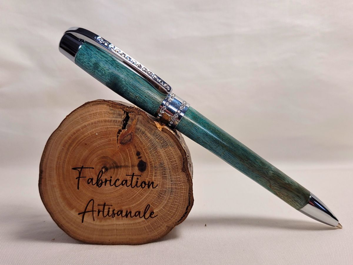 Stylo Princesse bleu aux reflets turquoise sur rondin gravé Fabrication artisanale — stylo en bouleau teinté, chrome et strass blancs, symbole d’un savoir‑faire artisanal français.