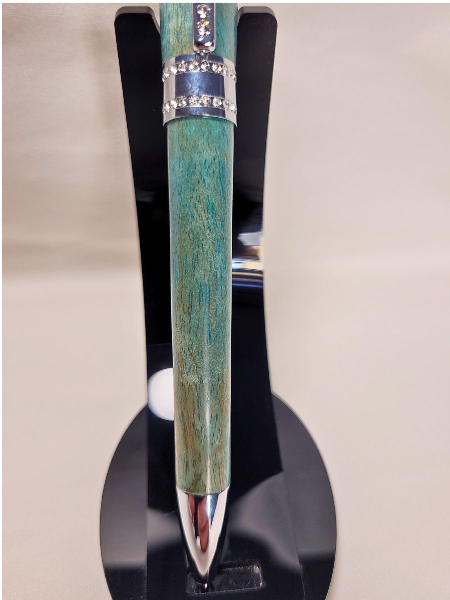 Stylo Princesse bleu aux reflets turquoise présenté verticalement — stylo artisanal en bouleau, finition chromée brillante et incrustations de strass blancs scintillants.