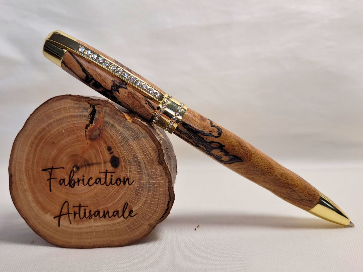 Stylo Princesse en hêtre échauffé sur rondin de bois — stylo artisanal doré avec strass blancs, bois veiné naturel, création raffinée et fabrication artisanale.