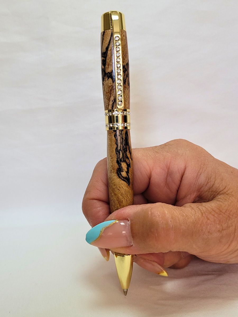 Stylo Princesse en hêtre échauffé tenu en main — stylo artisanal en bois veiné, finition or et strass blancs, mécanisme twist Parker, élégance et confort d’écriture.