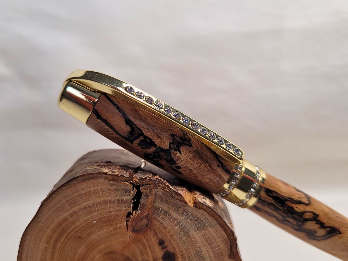 Stylo Princesse en hêtre échauffé posé sur support gravé Fabrication artisanale — stylo en bois noble, placage or et strass blancs, symbole d’un savoir‑faire français.