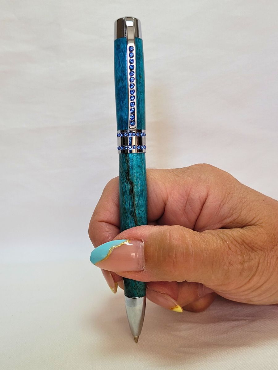 stylo artisanal en hêtre échauffé bleu, finition chromée et pierres bleues, mécanisme twist Parker, prise en main confortable.
