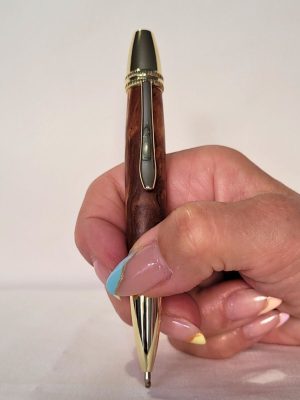 Stylo Alliance en bois de cerisier et finitions dorées tenu en main, système twist avec cartouche type Parker – design élégant et ergonomique.