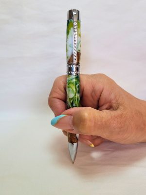 Stylo Princesse hybride tenu en main — stylo artisanal en bois et résine époxy blanc‑vert, finition chrome et strass blancs, confort d’écriture et design raffiné.