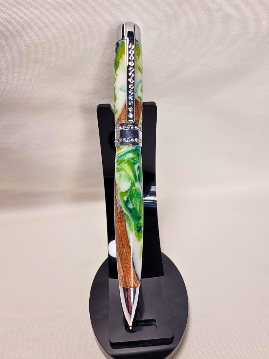 Stylo Princesse hybride en hêtre et résine époxy sur support noir — stylo artisanal marbré blanc et vert, placage chromé et strass blancs, modèle élégant et original.