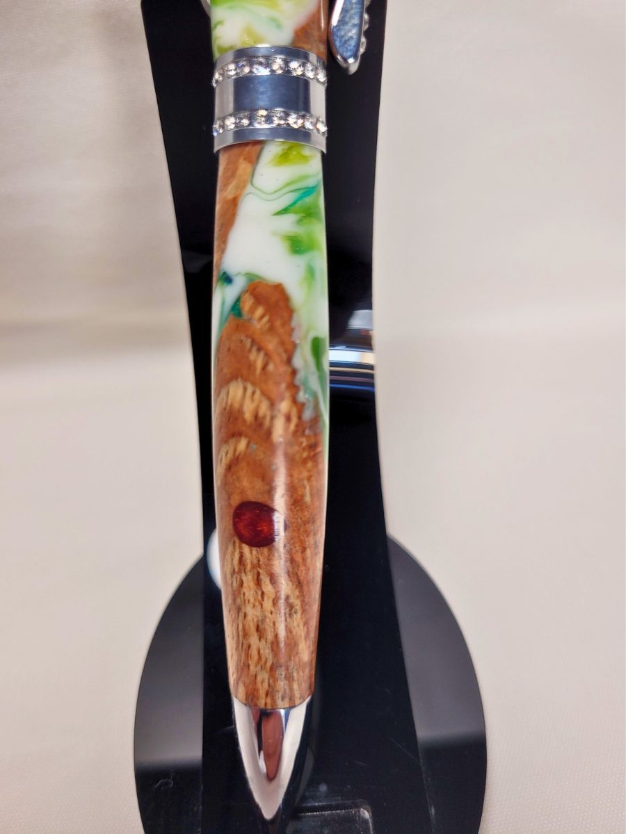 Stylo Princesse hybride présenté verticalement sur support noir — stylo artisanal en hêtre et résine époxy blanc‑vert, finition chromée brillante et strass blancs scintillants.