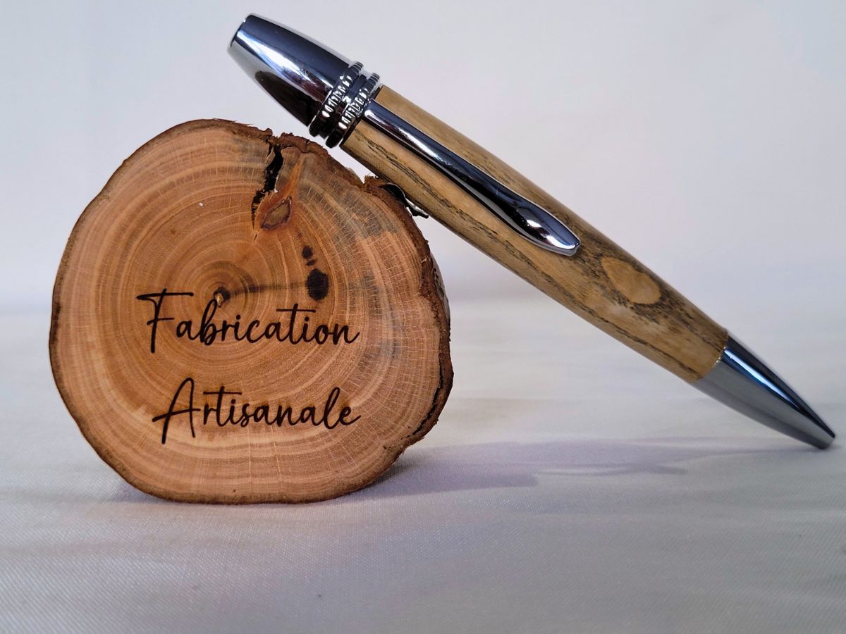 Stylo Alliance en bois de frêne et finitions chromées posé sur rondin gravé “Fabrication artisanale” – modèle élégant et naturel.