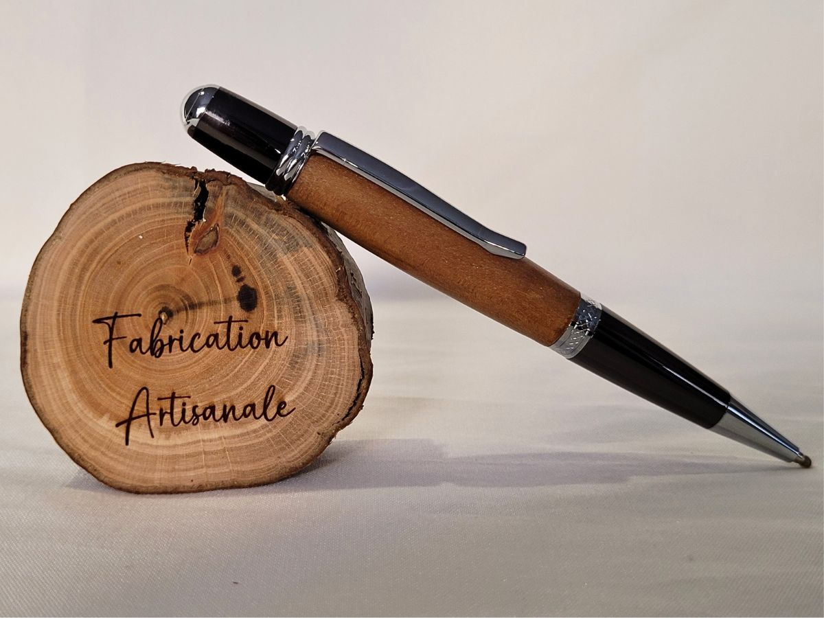 Stylo bille Élégance en bois de cerisier avec finition noire brillante et attributs chromés sur support Fabrication Artisanale - Atelier du Val des Anges