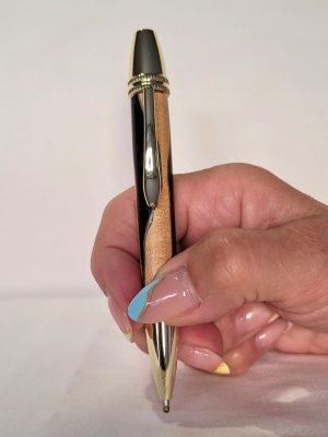 Stylo Alliance en bois de charme et ébène avec placage or, tenu en main – design yin‑yang clair et sombre, fabrication artisanale française.