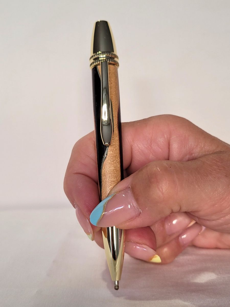 Stylo Alliance en bois de charme et ébène avec placage or, tenu en main – design yin‑yang clair et sombre, fabrication artisanale française.
