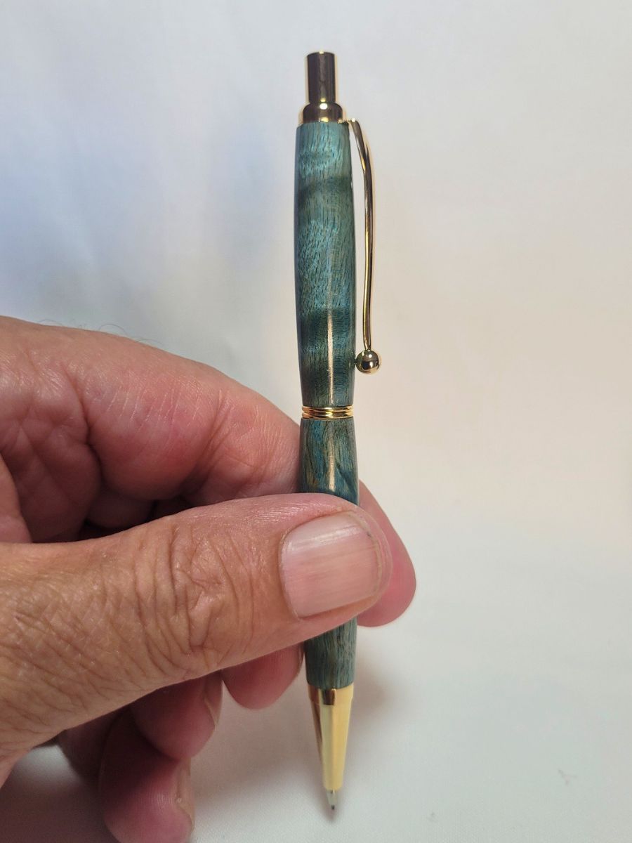 Porte‑mine artisanal en bois de bouleau teinté bleu, finition dorée, tenu en main pour montrer la finesse du design