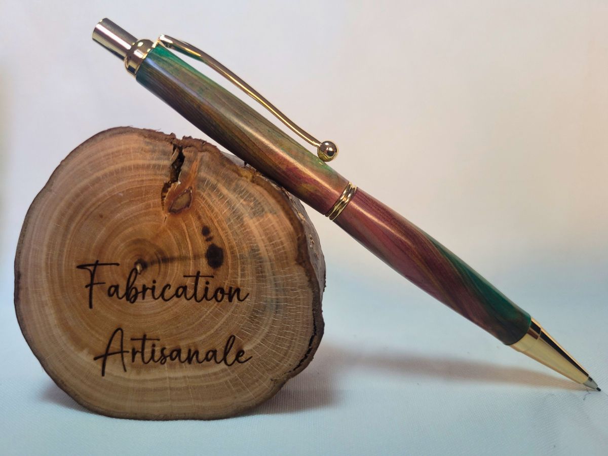 Porte‑mine artisanal en bois de genévrier teinté vert et rouge, placage doré, posé sur rondin gravé « Fabrication Artisanale »
