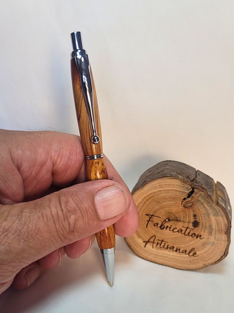 Porte‑mine artisanal en bois de padouk tenu en main, finition chromée brillante