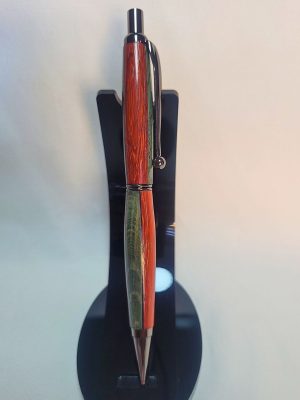 Porte‑mine artisanal en padouk, hêtre teinté bleu et placage noir, finition chromée avec épingle boule et mécanisme clic, sur support noir.