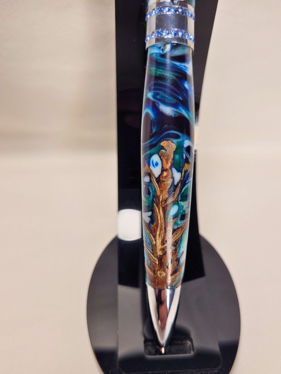 Stylo artisanal Princesse en pomme de pin et résine époxy bleu, blanc et émeraude, finition chrome et strass bleus, détail du corps.