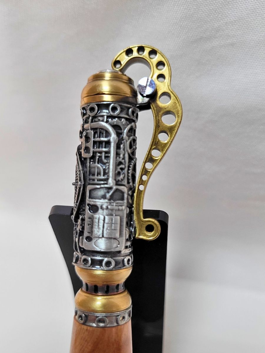 "Détail du haut du stylo steampunk en bois de bouleau, engrenages argentés et levier doré perforé"