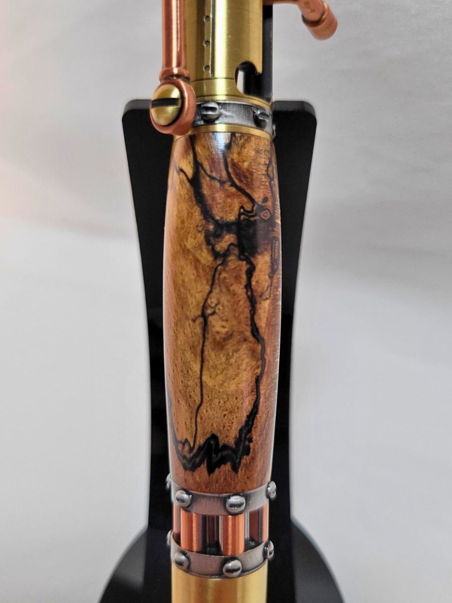 "Vue rapprochée du corps du stylo steampunk en hêtre échauffé, veinage sombre et détails métalliques"