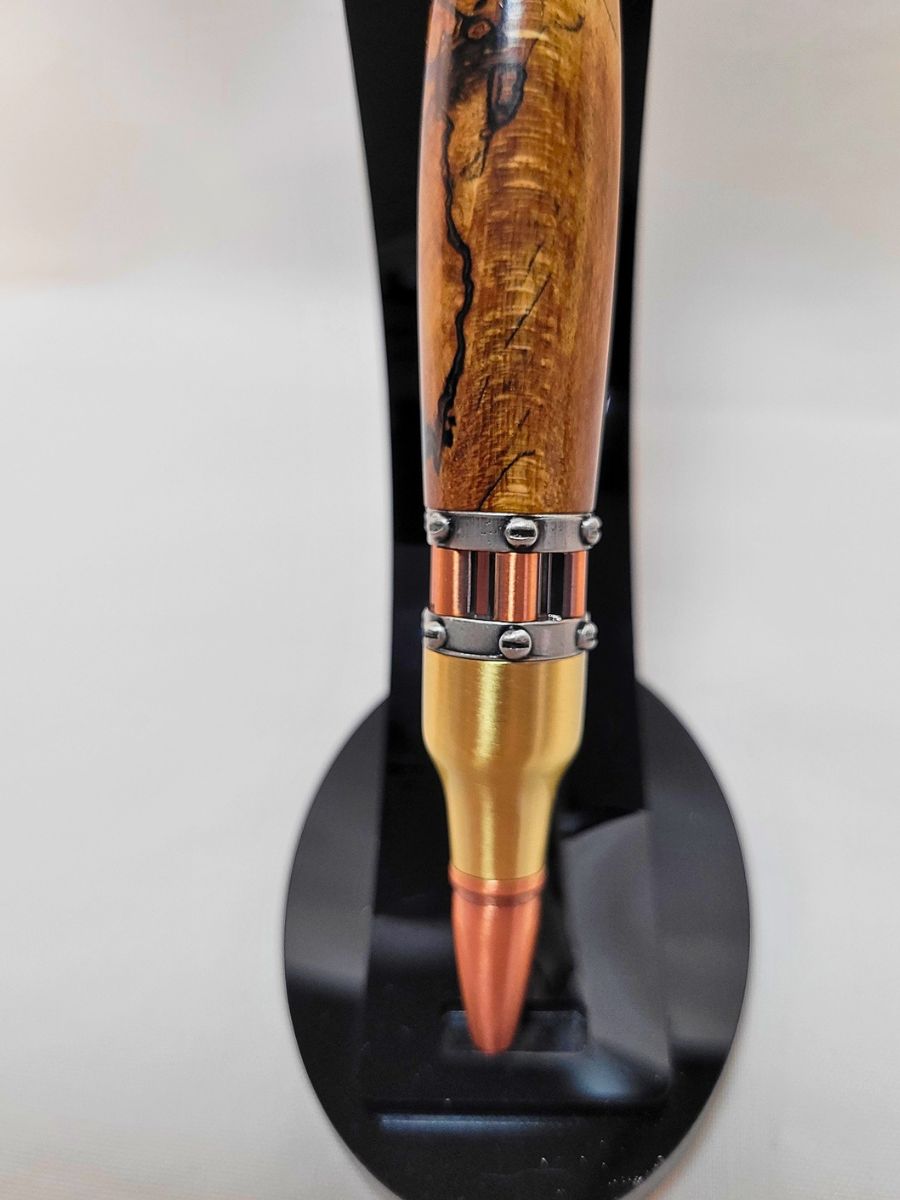 "Stylo steampunk artisanal en hêtre échauffé, pointe en cuivre et bagues rivetées en étain sur support noir"