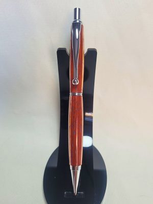 Porte‑mine artisanal en bois de padouk, frêne et bouleau, finition chromée avec épingle boule et gomme intégrée, sur support noir.
