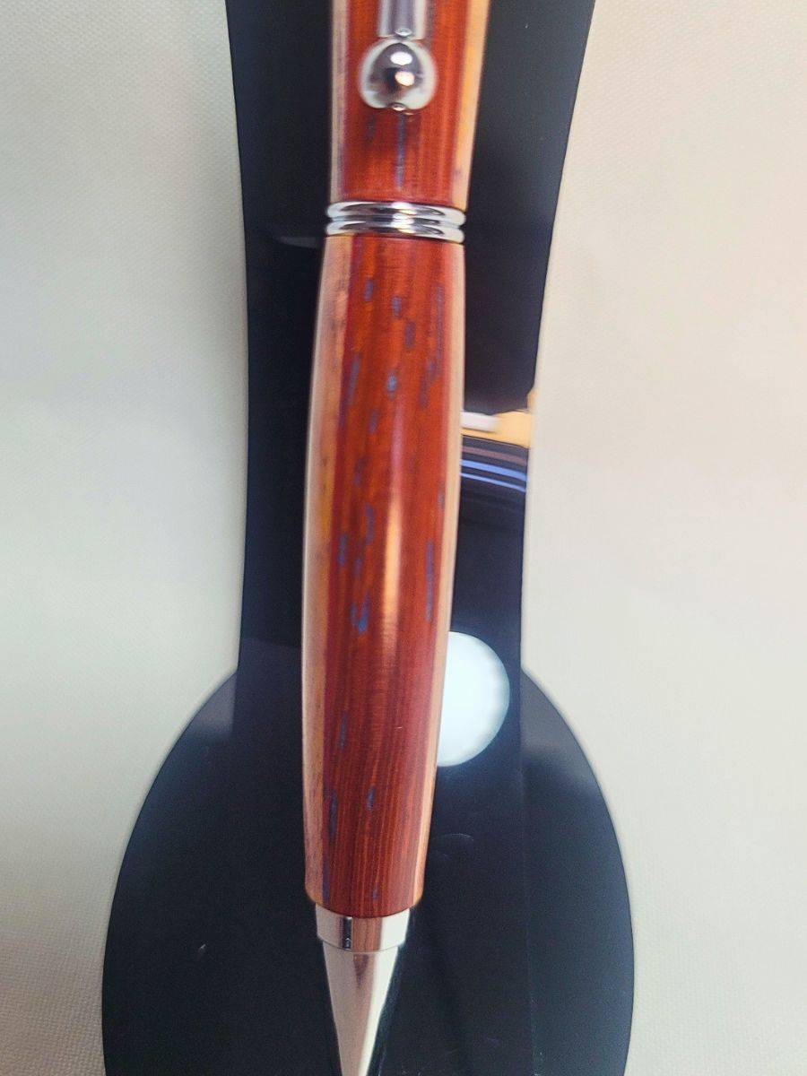 Détail du porte‑mine artisanal en bois de padouk, frêne et bouleau, finition chromée, mécanisme clic pour mines 0,5 mm.