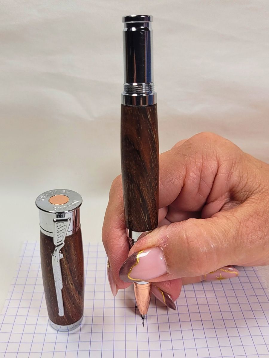 Roller artisanal en palissandre avec pointe ogive cuivrée et cartouche Schmidt Ceramic en situation d'écriture