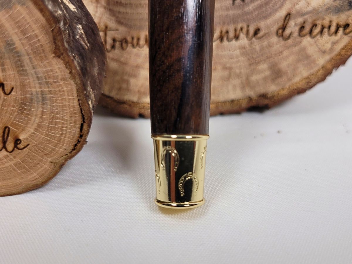 Bague centrale décorative dorée sur stylo roller en wacapou aux veines foncées et élégantes