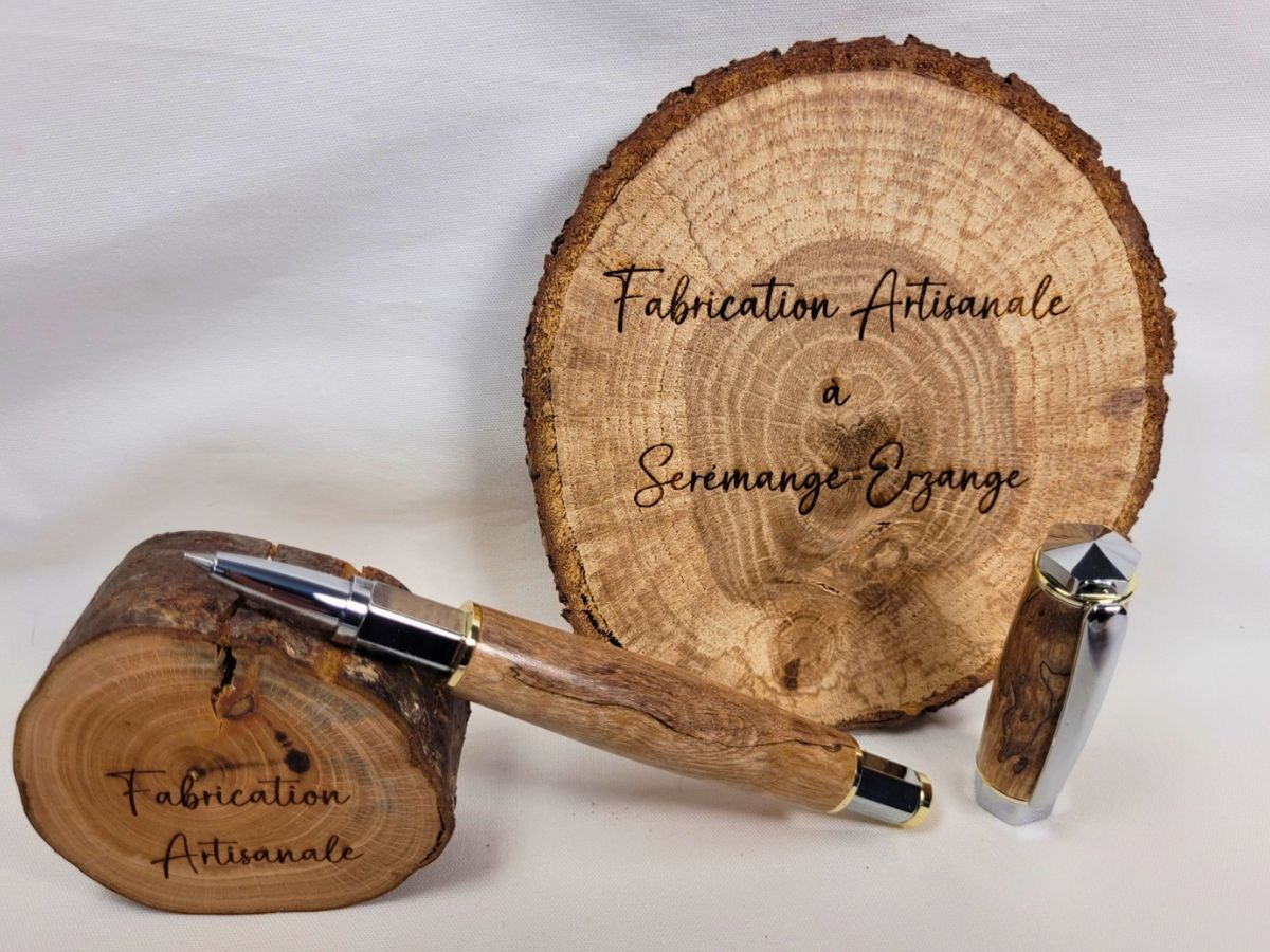 Stylo roller artisanal en bouleau échauffé avec finition chromée, présenté ouvert avec capuchon magnétique, mettant en valeur les veinures naturelles et uniques du bois.