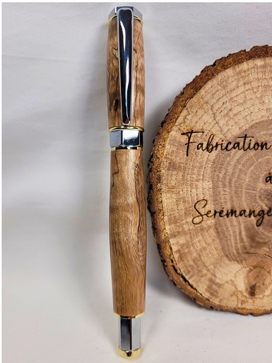 Stylo roller haut de gamme en bois de bouleau échauffé présenté verticalement avec placage chrome et bagues dorées