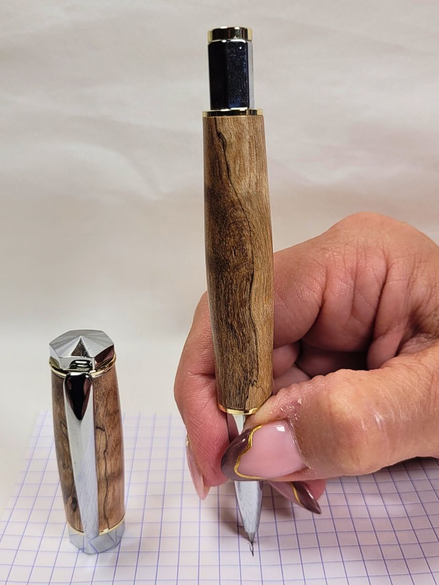 Détail d'un stylo roller en bouleau échauffé lors de l'écriture, capuchon magnétique et éléments métalliques hexagonaux chromés