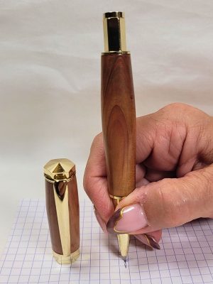 Stylo roller en bois de genévrier plaqué or en situation d'écriture, équipé d'une cartouche Schmidt Ceramic Fine pour une écriture fluide et précise.