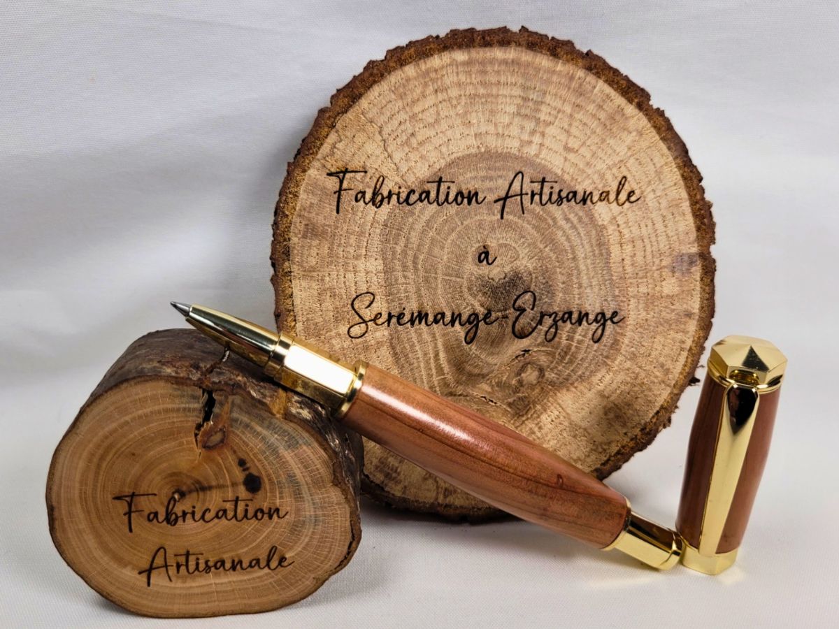 Détail d'un stylo roller en bois de genévrier aux veinures naturelles remarquables, finition plaquée or et fabrication artisanale française.
