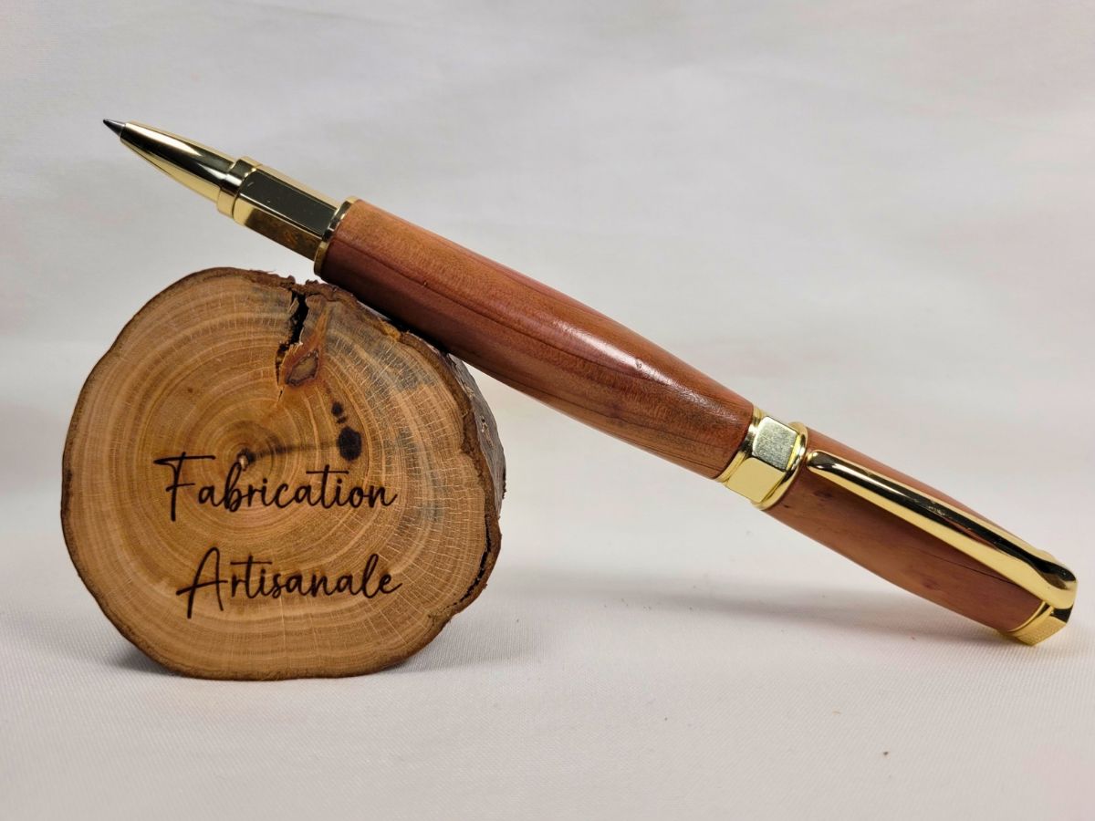 Stylo roller artisanal en bois de genévrier avec capuchon magnétique plaqué or, présenté ouvert pour mettre en valeur son élégante finition et son écriture fluide.