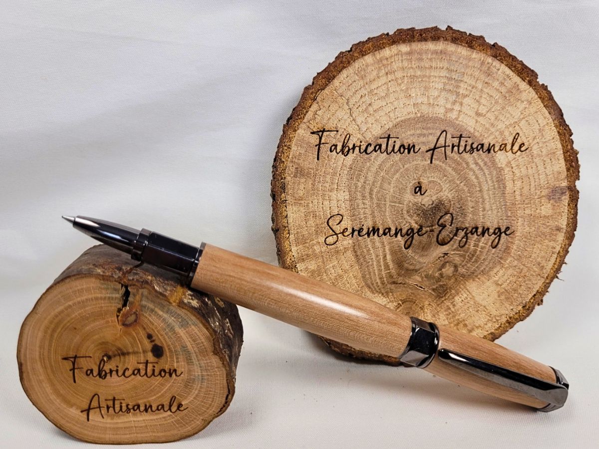 Stylo artisanal en bois de prunier présenté sur tranche de bois fabrication française