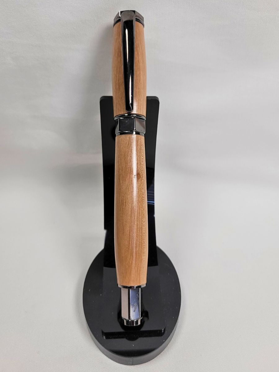 Stylo roller artisanal en bois de prunier avec finition noire hexagonale présenté sur support noir