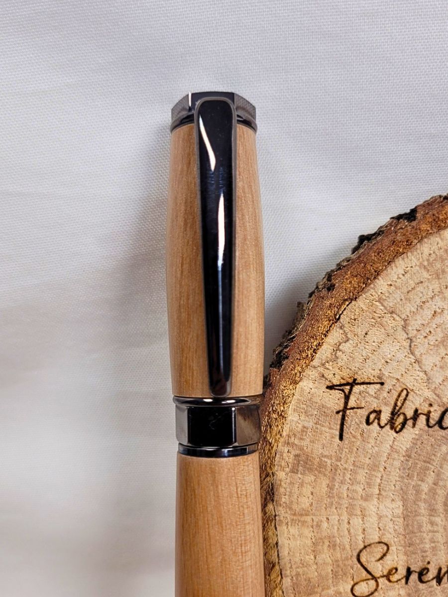 Détail du capuchon d'un stylo roller artisanal en bois de prunier avec placage noir brillant