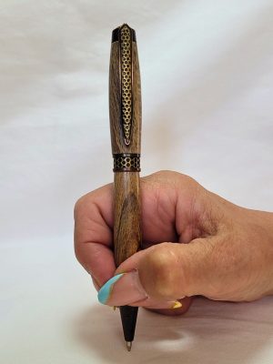 Stylo artisanal en bois de Hêtre avec clip et bague bronze motif nid d'abeille, mécanisme Twist et recharge Parker G2 en situation d'écriture