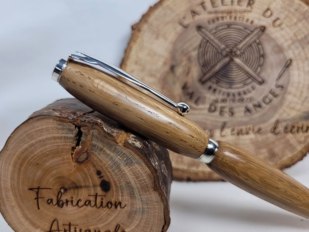Stylo artisanal en chêne massif, placage chrome brillant, posé sur bois gravé L’Atelier du Val des Anges, Fabrication artisanale.