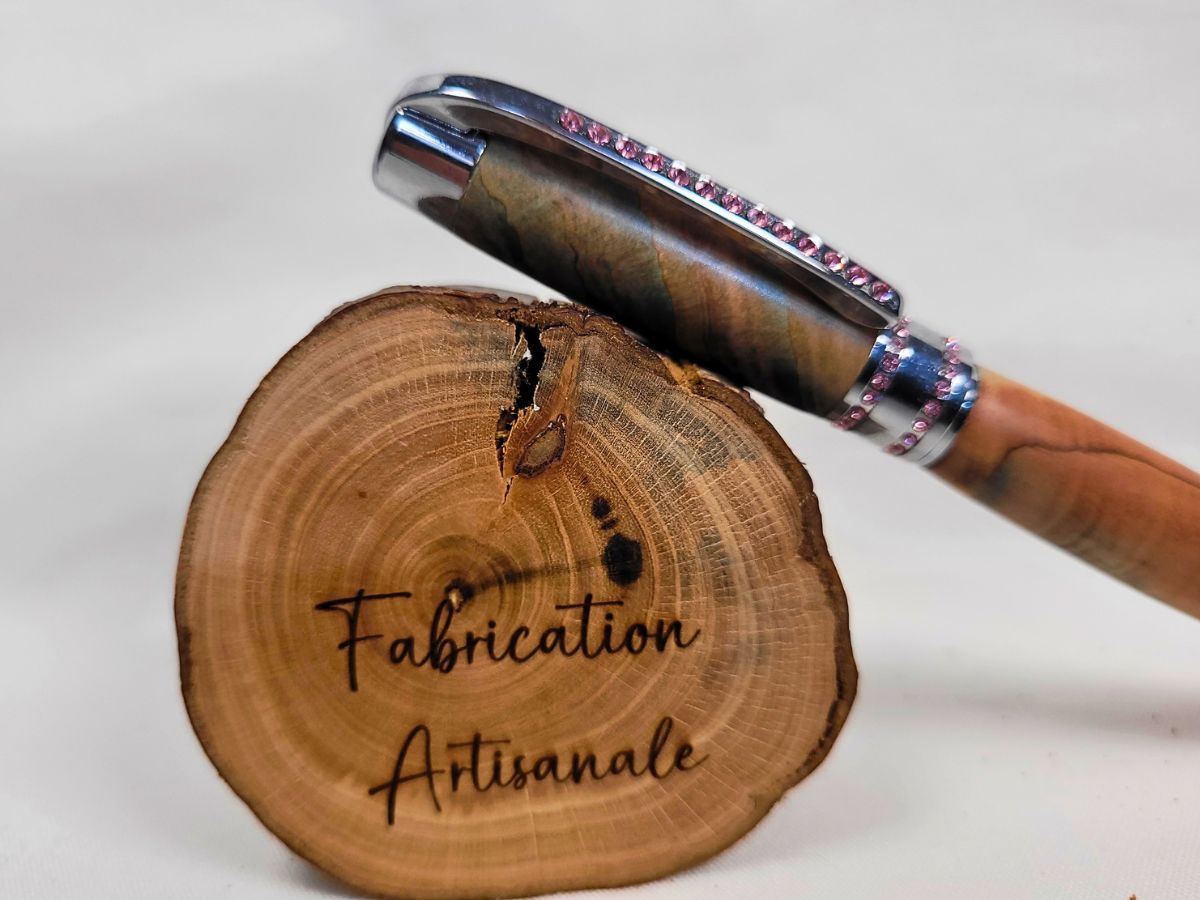 Gros plan sur les strass roses d'un stylo artisanal en bois de genévrier
