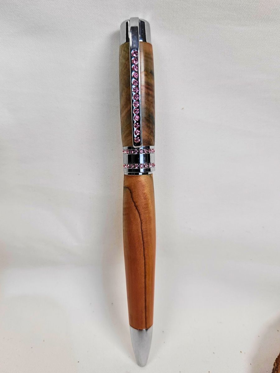 Stylo Princesse en genévrier avec veines naturelles contrastées, finition chromée brillante et strass roses, pièce unique fabriquée à la main