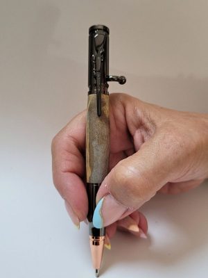 Stylo bille artisanal en bois avec épingle en forme de fusil, finition noir et cuivre, démonstration de la prise en main et de l'écriture