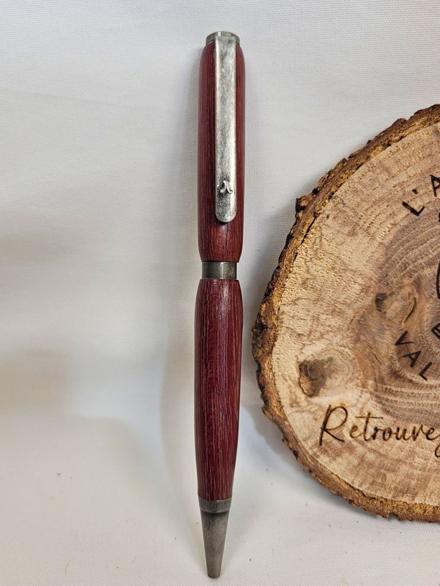 Stylo slim artisanal en bois d’amarante de Guyane, mécanisme en étain massif, sigle lambda, présenté verticalement sur fond clair.