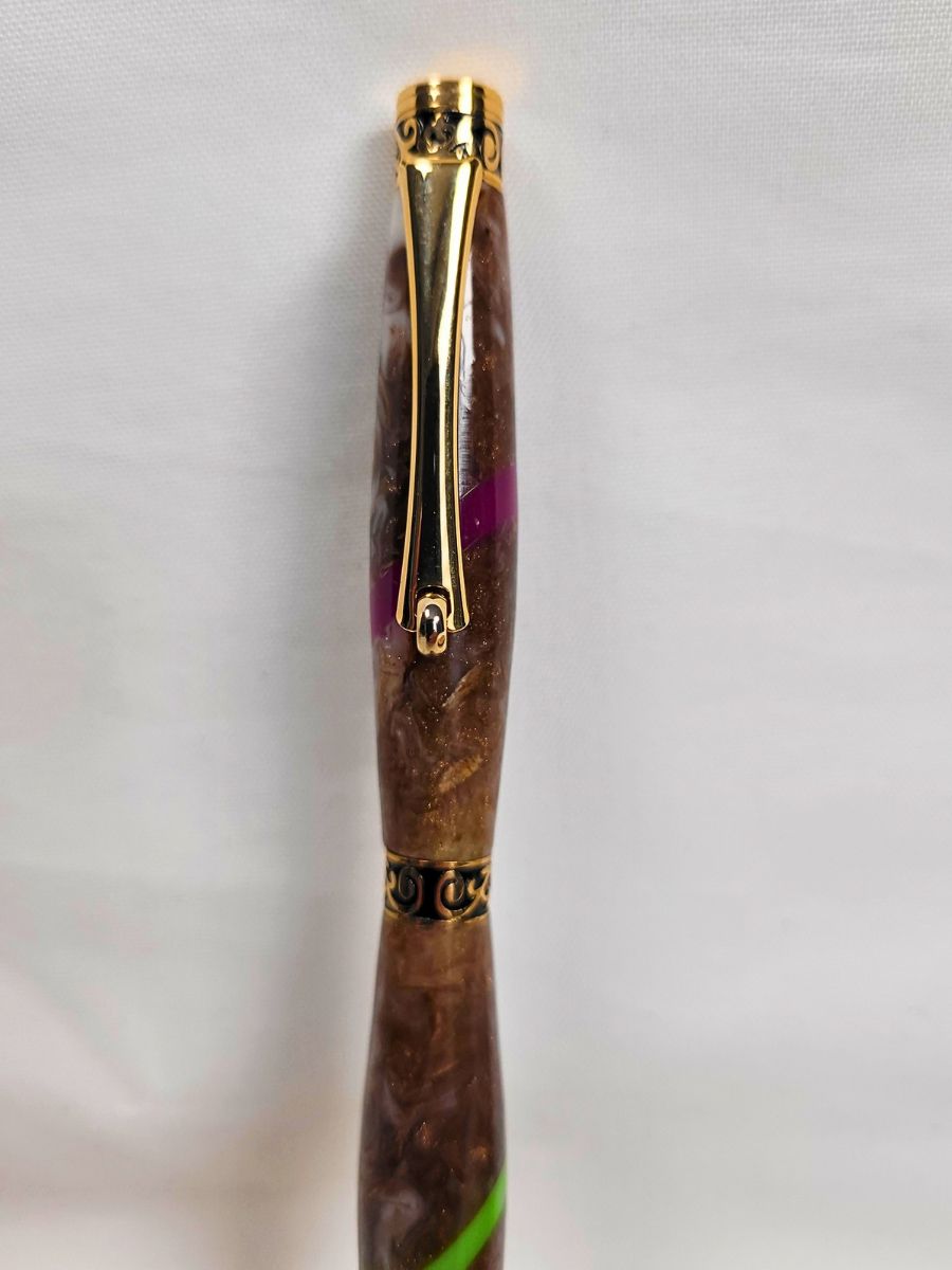 Détail du clip doré et de la résine époxy marbrée d'un stylo artisanal fait main