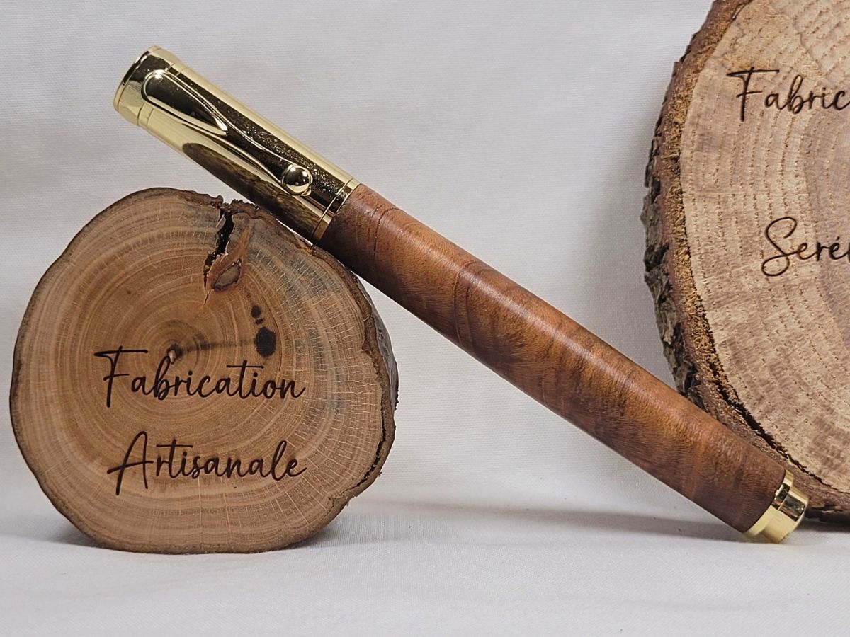 Stylo roller magnétique en bois de cerisier avec placage doré, mettant en valeur les fibres traversantes du bois et son veinage naturel unique.