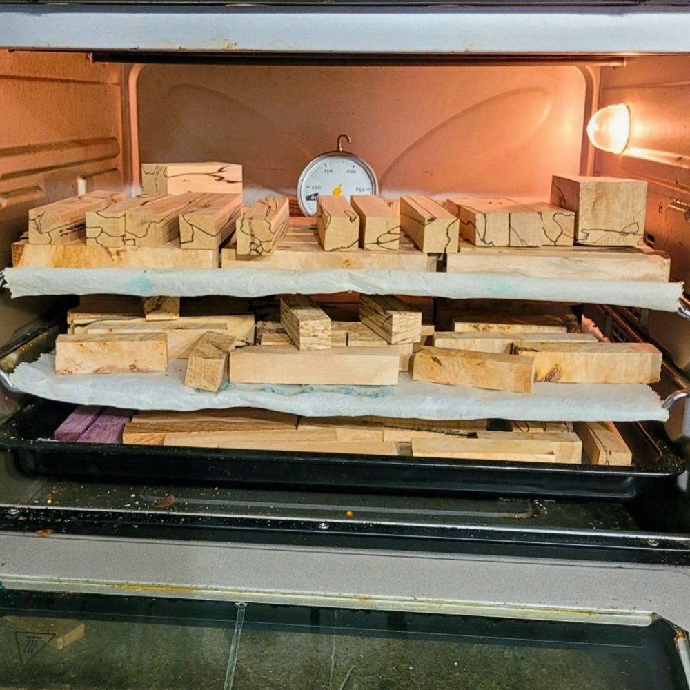 Carrelets de bois échauffé disposés sur plusieurs niveaux dans un four de séchage, présence de lignes de zone naturelles caractéristiques du bois échauffé, préparation artisanale des matériaux destinés à la fabrication de stylos uniques Séchage contrôlé de carrelets en bois échauffé dans l'atelier du Val des Anges, étape permettant de stabiliser l'humidité du bois avant le tournage de stylos artisanaux et d'objets en bois d'exception