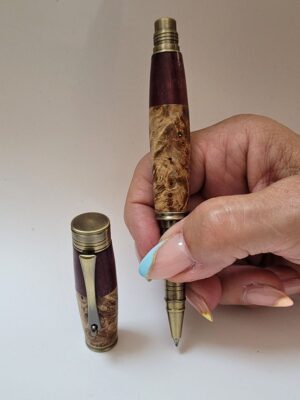 Roller artisanal en loupe de bouleau et amarante avec finition bronze tenu en main