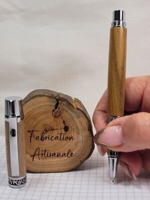 roller artisanal en bois de cerisier chromé brillant tenu en main, capuchon retiré, bague ciselée noire et chrome, fabrication artisanale française