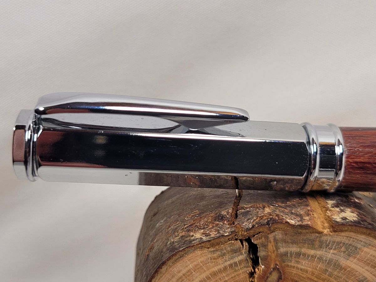 Détail du capuchon magnétique hexagonal chromé d’un stylo roller en amarante de Guyane fabriqué à la main